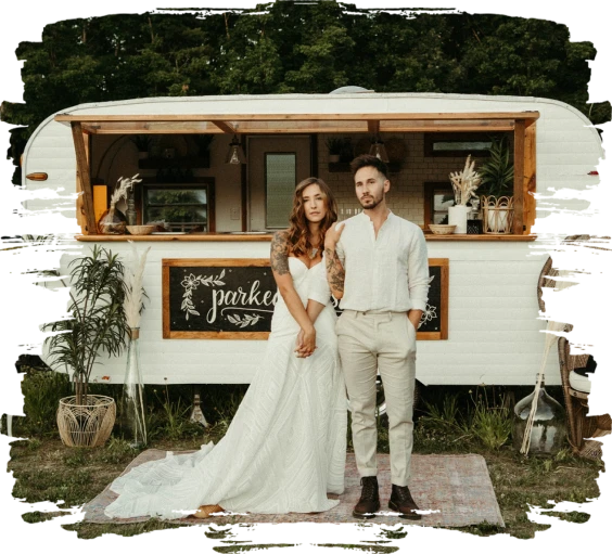 A bride and groom in front of the Vino Valet camper bar